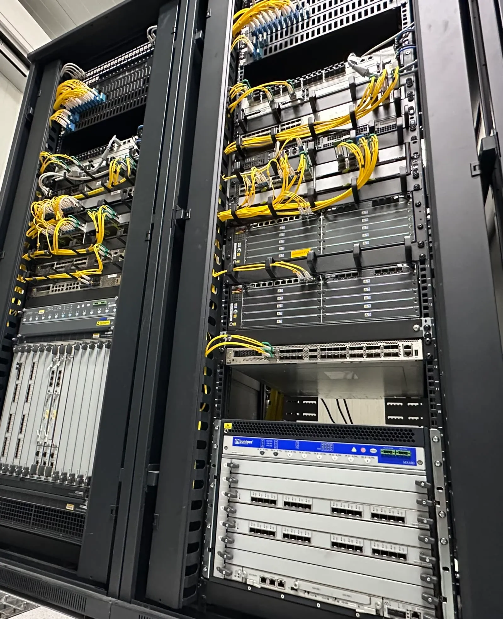 Dos bastidores de un centro de datos con equipos de red y cables de fibra óptica amarillos