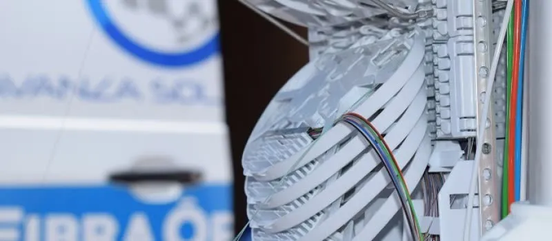 Bandejas de empalme de fibra óptica dentro de una caja de distribución, con una furgoneta rotulada desenfocada al fondo
